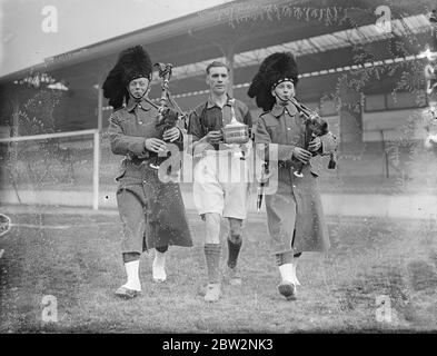 Zweite Batterie Schotten Guards gewinnen Bulldog Challenge Cup . Die zweite Batt Scots Guards gewann den Bulldog Challenge Cup, als sie die 3. Batt Coldstream Guards im Finale auf dem Fußballplatz Tottenham besiegten. Foto zeigt, Piping Lance Sergeant Howcroft, Kapitän der Schotten Wachen aus dem Feld mit der Tasse. 25 April 1934 . Stockfoto