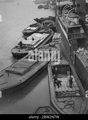 Schiffe in ' Tariff Day ' Rennen zu entladen. Viele Schiffe fahren mit Höchstgeschwindigkeit nach England in der Hoffnung, rechtzeitig vor 17 Uhr am Montag in den Hafen zu gelangen, um die 10 Prozent Zölle, die am Tag des Tarifs in Kraft treten, nicht mehr auf die Ladungen zu zahlen - Dienstag, Entladen von Waren aus der SS Lingestroom von Amsterdam in Hays Wharf, London. 26 Februar 1932 26 Februar 1932 30er, 30er, 30er, 30er, 30er, 30er, 30er, 30er Stockfoto