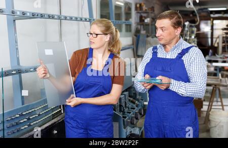 Frau und ihr männlicher Kollege arbeiten in der Glaswerkstatt Stockfoto