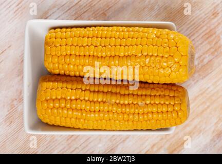 Koben frisch gekochten Mais auf weißem Teller serviert. Leckere vegetarische Snacks Stockfoto