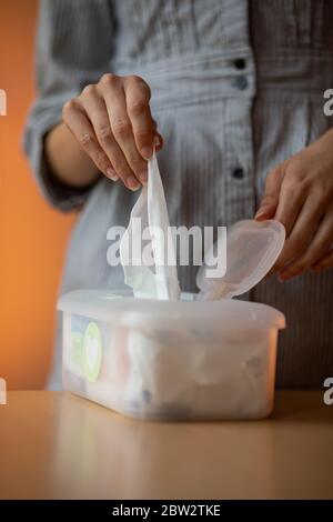 Nasse Tücher sind universell und praktisch: Frau Hand nehmen Sie ein Tuch aus großen Kunststoff-Box-Paket für die Reinigung, zu Hause, drinnen Stockfoto