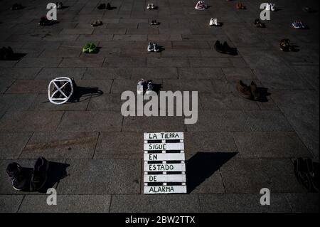 Madrid, Spanien. Mai 2020. Extinction Rebellion Aktivist protestiert während einer Performance, bei der mehr als 1000 Schuhe auf dem Sol Square auf dem Boden liegen, um Bürgerbeteiligung, soziale Gerechtigkeit und Maßnahmen gegen die Klimakrise und eine grüne Erholung nach der Coronavirus-Krise (COVID-19) zu fordern. Text lautet: Die Erde ist immer noch in Alarmzustand. Quelle: Marcos del Mazo/Alamy Live News Stockfoto