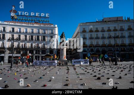 Madrid, Spanien. Mai 2020. Extinction Rebellion Aktivist protestiert während einer Performance, bei der mehr als 1000 Schuhe auf dem Sol Square auf dem Boden liegen, um Bürgerbeteiligung, soziale Gerechtigkeit und Maßnahmen gegen die Klimakrise und eine grüne Erholung nach der Coronavirus-Krise (COVID-19) zu fordern. Quelle: Marcos del Mazo/Alamy Live News Stockfoto