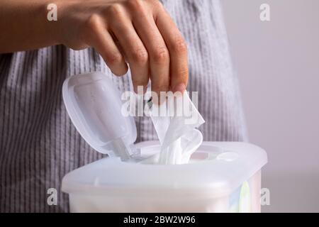 Nasse Tücher sind universell und praktisch: Frau Hand nehmen Sie ein Tuch aus großen Kunststoff-Box-Paket für die Reinigung, zu Hause, drinnen Stockfoto