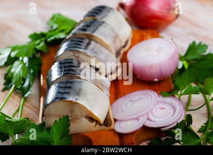 Beliebte Vorspeise aus leicht gesalzenen Makrelen Scheiben mit Gemüse und Zwiebeln auf Holz Schneidebrett Stockfoto