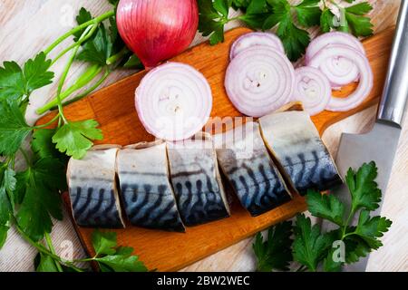 Beliebte Vorspeise aus leicht gesalzenen Makrelen Scheiben mit Gemüse und Zwiebeln auf Holz Schneidebrett Stockfoto