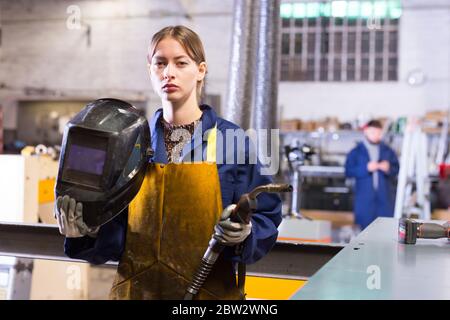 Junge Frau, die Schweißer für Bauarbeiten in der Werkstatt verwendet Stockfoto