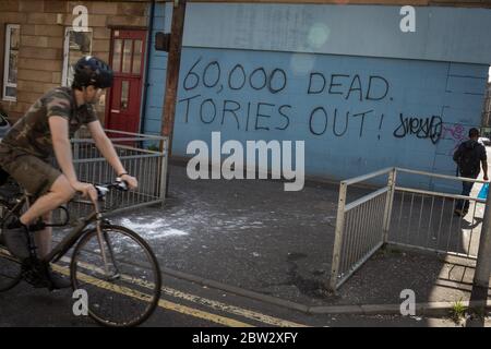 Glasgow, Großbritannien, 29. Mai 2020. Graffiti mit der Aufschrift '60,000 Dead, Tories Out!' Ist an einer Mauer im Stadtteil Govanhill der Stadt erschienen und zeigt lokale Wut über die Politik und den Umgang mit dem Coronavirus Covid-19 Gesundheitspandemie durch die konservative Regierung Großbritanniens unter der Leitung von Premierminister Boris Johnson. In Glasgow, Schottland, am 29. Mai 2020. Foto: Jeremy Sutton-Hibbert/Alamy Live News. Stockfoto