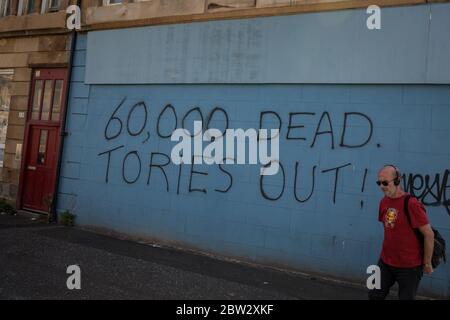 Glasgow, Großbritannien, 29. Mai 2020. Graffiti mit der Aufschrift '60,000 Dead, Tories Out!' Ist an einer Mauer im Stadtteil Govanhill der Stadt erschienen und zeigt lokale Wut über die Politik und den Umgang mit dem Coronavirus Covid-19 Gesundheitspandemie durch die konservative Regierung Großbritanniens unter der Leitung von Premierminister Boris Johnson. In Glasgow, Schottland, am 29. Mai 2020. Foto: Jeremy Sutton-Hibbert/Alamy Live News. Stockfoto