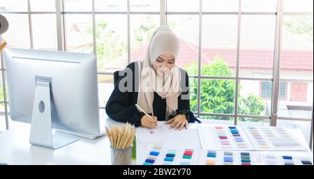 Kleine Unternehmen von Moslem-Frauen Modedesignerin, Die Mit Smartphone und Tablet Mit Kleider im Bekleidungsgeschäft arbeitet und verwendet Stockfoto