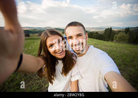 Selfie-Portrait eines glücklichen Paares, das im Zelt auf den Bergen zeltet. Camper lächeln glücklich im Freien im Wald. Glückliche Menschen, die Spaß haben. Stockfoto