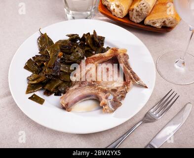 Gebratenes Schweinekotelett mit Gemüsegarnieren aus gekochten grünen Bohnen Stockfoto