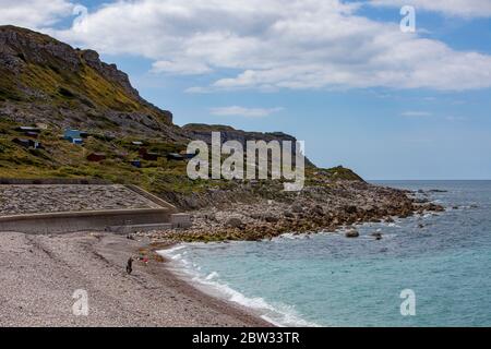 Leute genießen einen frühen Morgenspaziergang am Chesil Beach in der Nähe von Weymouth, Dorset mit Portland im Hintergrund Stockfoto