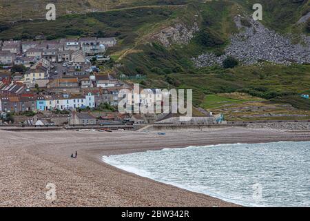 Leute genießen einen frühen Morgenspaziergang am Chesil Beach in der Nähe von Weymouth, Dorset mit Portland im Hintergrund Stockfoto