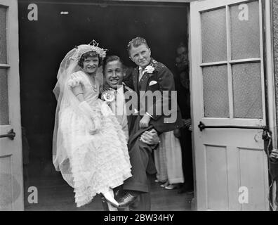 England ' s kleinste Braut und Bräutigam heiraten in Mitcham. Miss Dorothy Kathleen Griffiths, die nur 3 Fuß 10 Zoll groß ist, und Herr Vivian Pascoe, der zwei Zoll größer ist, wurden in St Barnabas Kirche verheiratet, Mitcham, Surrey. Mr A G Griffiths, der beste Mann, hält die Braut und Bräutigam in den Armen. Bis 14. August 1932 Stockfoto