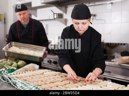 Professionelle female Koch in Vorbereitung der Eiszapfen Brötchen aus frischen Nudeln Blätter eingelegt und Hackfleisch Stockfoto