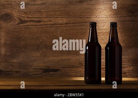 Zwei geschlossene Flaschen dunkles Bier auf rustikalem Hintergrund. Stockfoto
