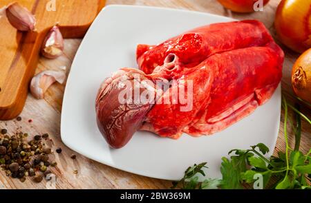 Rohe Fleischablagen, frische Lammlungen und Herz mit Gewürzen auf Holztisch Stockfoto