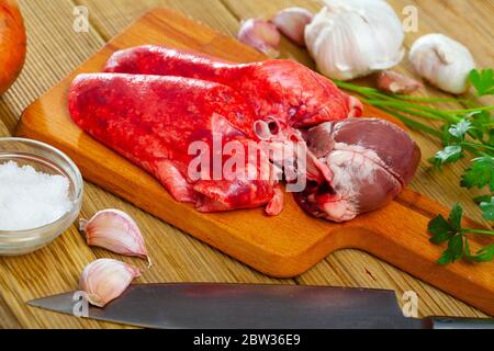 Rohe Fleischablagen, frische Lammlungen und Herz mit Gewürzen auf Holztisch Stockfoto