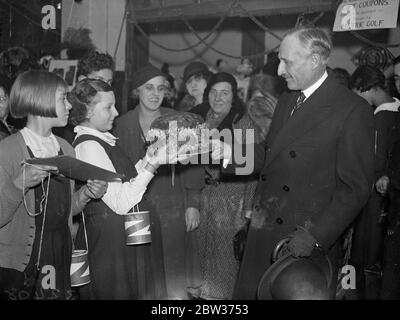 Französischer Botschafter eröffnet Weihnachtsmarkt in London . M Corbin, der französische Botschafter, eröffnete eine Weihnachtsmesse in der Mädchenhalle von Notre Dame de France, Leicester Square, London. Foto zeigt ; M Corbin Beurteilung des Gewichts eines Kuchens . 15 Dezember 1933 Stockfoto