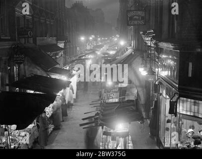 Weihnachtseinkäufe in der Berwick Street 's helle Lichter. Die unzähligen Lichter der Berwick Street, vor Piccadilly, London, einer der bekanntesten Märkte in der Metropole. Derzeit machen die Außenverkäufer einen flotten Weihnachtshandel. 15 Dezember 1933 Stockfoto