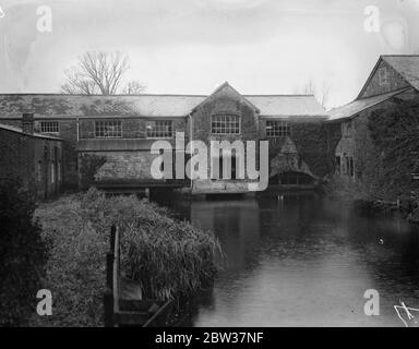 Weben Hampshire tweeds an einer alten Mühle, die für hundert Jahre untätig stand. Eine alte Mühle bei Fordingbridge im New Forest, Hampshire, die seit 100 Jahren untätig geblieben ist, ist wieder zum Leben erweckt worden. Es ist Weben in Tweeds Wolle aus den Herden, die auf Salisbury Plain grasen, und es wird gehofft, Hampshire Tweeds so berühmt wie die Harris-Sorte zu machen. Die Maschinen, für die die alten Schleusen sind die Macht sind gebracht worden aus Westmorland, und Experten Wollmänner wurden auch aus dem Norden gebracht. Der neue Mühlenbesitzer ist Major C T Napier . Die alte Mühle, wo jetzt das Unkraut ist Stockfoto