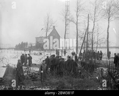 Zehn bei einem britischen Verkehrsflugzeug-Crash getötet. Acht Passagiere, der Pilot und der erste Offizier wurden getötet, als das Imperial Airways-Flugzeug, Apollo, von Brüssel nach London flog, in den Antennenmast des Ruysselde-Radiosenders in der Nähe von Brügge, Belgien stürzte und in Flammen aufbrach. Foto zeigt ; Menschen, die die Trümmer des abgestürzten Flugzeug suchen . 31 Dezember 1933 Stockfoto