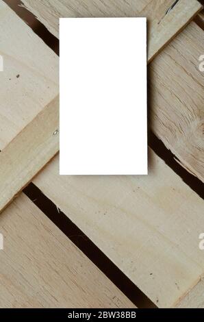 Geometrischer Holzhintergrund mit einer leeren Visitenkarte. Gekreuzte Holzplanken. Hintergrund für Multitasking. Blick von oben. Selektiver Fokus. Stockfoto