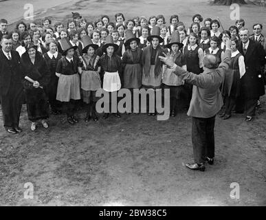 Walisischer Kinderchor in Ealing in Nationalkostüm. Kinder des Aberaman Jugendchors von Wales übten auf Ealing Green, bevor sie ein Konzert im Rathaus von Ealing gaben. Der Chor hat über 300 Preise gewonnen, darunter 11 nationale Auszeichnungen. Foto zeigt, der Chor probt auf Ealing Green unter der Leitung ihres Dirigenten, Herrn Mitchelmore. 11. April 1934 Stockfoto