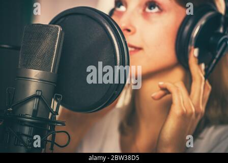 Weibliche Voiceover Lautsprecher in ihrem 20s Inside Recording Studio vor dem professionellen Mikrofon. Stockfoto