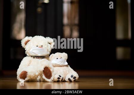 Zwei Teddybären in medizinischen Masken sitzen in der Nähe der Haustür im Flur des Hauses. Kopierbereich Stockfoto