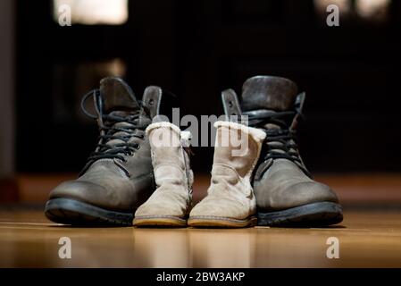 Alte Stiefel für Erwachsene und Kinder stehen nebeneinander Der Boden im Flur Stockfoto