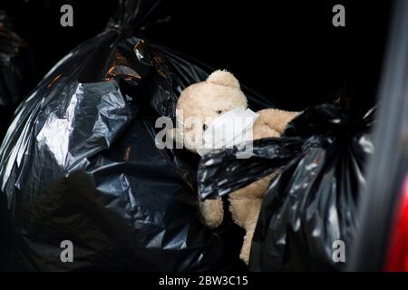Ein Teddybär mit einem medizinischen Verband im Gesicht Liegt auf den Abfallsäcken Stockfoto