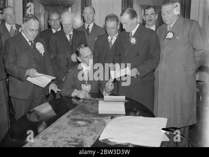 SAir Malcolm Campbell Hände in seiner Wahl Nominierung. Sir Malcolm Campbell, der Rennfahrer, der National Natinal Kandidat in Deptford, in seiner Nominierung Papier an den Bürgermeister von Deptford, Ratsmitglied J E Pearson, in Deptford Town Hall. Foto zeigt, Sir Malcolm Campbell Übergabe seiner Nominierung an Ratsmitglied, J E Pearson, der Bürgermeister von Deptford. Links ist Alderman W H Green, Sir Malcolm' s Gegner. November 1935 Stockfoto