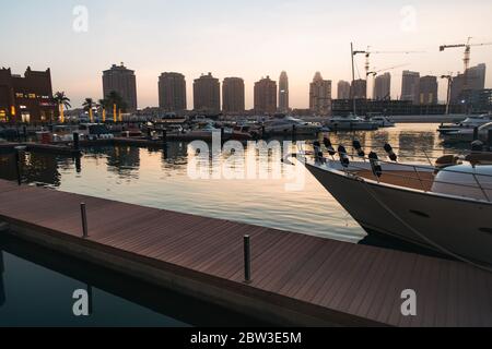 Abenddämmerung entlang der Marina Promenade an der Pearl-Qatar, einer künstlichen Wohninsel in Doha, Katar. Marsa Arabia Island wird im Bau gesehen Stockfoto