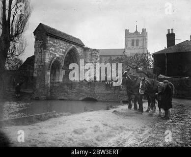 Überrest einer glorreichen Vergangenheit . Ein Team von Farmpferden durch die alte Gateway in Waltham Abbey und die Abbey Kirche, die 875 Jahre alt ist. 15. Januar 1935 Stockfoto