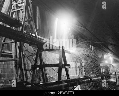 Eine nächtliche Ansicht der Tag und Nacht Arbeit, um die Schäden an der Ozeandampfer zu reparieren, Aquitania durch raue Meere gemacht. Bild zeigt ; Sparks fliegen, während die Schweißer auf die Aquitania in der neuen Gravierstation in Southampton gehen. 14. Januar 1935 Stockfoto