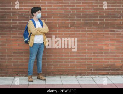 Kind mit medizinischen Maske und Rucksack gehen zur Schule im Freien Stockfoto