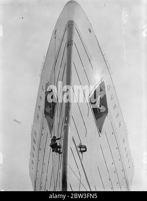 Maler ' s großen Job ! . Nun, da die "Queen Mary" im Trockendock ist, wird der kolossale Großteil des riesigen Liners im Vergleich zu der kleinen Armee von Malern und Handwerkern bei der Arbeit an ihrem Rumpf zu Vorteil gezeigt, Die wird in Vorbereitung für die nächsten Woche geschabt und bemalt. Die Propeller, die sie von Clyde herunterbrachten, wurden für andere von einem corsar-Pitch geändert. Foto zeigt, kriechend über die hoch aufragenden Bögen wie eine Fliege der Maler erneuert die Unterwassermarkierungen auf dem Rumpf der Queen Mary ' s in Southampton. 31 März 1936 Stockfoto