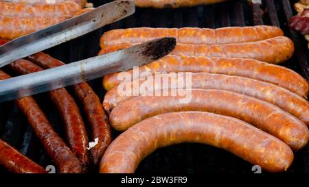 Gegrillte Würstchen und Grillzangen. Stockfoto