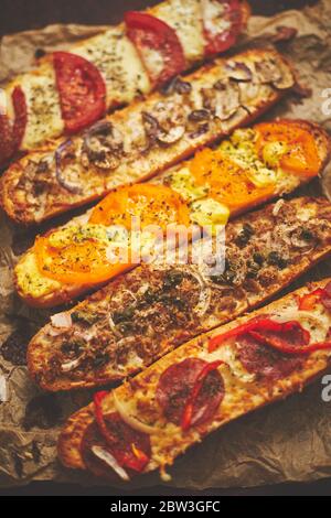 Zusammensetzung von heißen leckeren gebackenen Sandwiches mit verschiedenen Belägen. Käse, Thunfisch, Mozarella, Gewürze Stockfoto