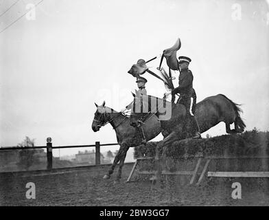 Kavallerie Proben für Royal Turnier . Unsattling ihre Reittiere über atemberaubende Sprünge und die Durchführung der schwierigsten Leistungen mit hervorragenden Reitsport, Troopers der Equitation School in Weedon, Northamptonshire, sind reheasring für die Royal Tournament, die bei Olympia im nächsten Monat eröffnet. Die Männer, die teilnehmen, werden von kleinen Kavallerieeinheiten der britischen Armee gepflückt. Foto zeigt, Sättel hoch in der Luft gehalten, Troopers der Equitation School einen schwierigen Sprung. 14. April 1936 Stockfoto