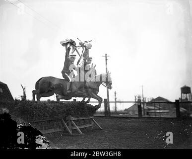 Kavallerie Proben für Royal Turnier . Unsattling ihre Reittiere über atemberaubende Sprünge und die Durchführung der schwierigsten Leistungen mit hervorragenden Reitsport, Troopers der Equitation School in Weedon, Northamptonshire, sind reheasring für die Royal Tournament, die bei Olympia im nächsten Monat eröffnet. Die Männer, die teilnehmen, werden von kleinen Kavallerieeinheiten der britischen Armee gepflückt. Foto zeigt, Sättel hoch in der Luft gehalten, Troopers der Equitation School einen schwierigen Sprung. 14. April 1936 Stockfoto