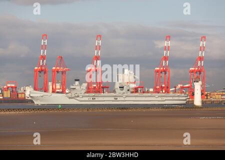 Liverpool, England. HMS Queen Elizabeth auf dem Fluss Mersey, vorbei an den roten Kranen des Liverpool Container Terminal. Stockfoto