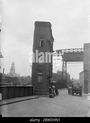 London ' s Flat Flats hoch über dem geschäftigen Hafengebiet, umgeben von Kränen und die Heckmasten der Welt ' s Schifffahrt, ist London ' s neugierig Gebäude. Isoliert an der Seite des Surrey Dock Canal das schmale Gebäude in der Nortthey Street, Limehouse, wird als Wohnblock verwendet. Foto zeigt: Londons kleinster und kuriosesten Wohnblock, an der Seite des Surrey Dock Kanals in der North Street, Limehouse. Juli 1936, 13 Stockfoto