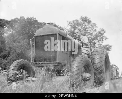 Sir Malcolm Campbell nimmt Traktor fahren. Sir Malcolm Campbell , der schneller an Land gefahren ist als jeder andere in der Welt ., fährt jetzt einen Traktor , eine der langsamsten Methoden der Fortbewegung und gefällt die Veränderung ! . Sir Malcoml ist mit dem Traktor, um das Gras für die neuen Erweiterungen zu seinem Golfplatz zu Hause schneiden, Headley Grove, Surrey. Foto zeigt, Sir Malcolm Campbell pilotieren den Traktor über das Gras in Headley Grove, Surrey. 11 Juli 1936 Stockfoto