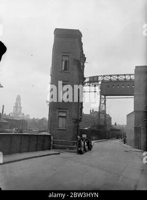 London ' s Flat Flats hoch über dem geschäftigen Hafengebiet, umgeben von Kränen und die Heckmasten der Welt ' s Schifffahrt, ist London ' s neugierig Gebäude. Isoliert an der Seite des Surrey Dock Canal das schmale Gebäude in der Nortthey Street, Limehouse, wird als Wohnblock verwendet. Foto zeigt: Londons kleinster und kuriosesten Wohnblock, an der Seite des Surrey Dock Kanals in der North Street, Limehouse. Juli 1936, 13 Stockfoto