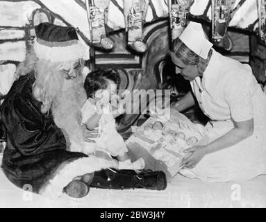 Exklusive Bilder der Dionne Quintuplets Weihnachtsfeier. Quint Puppen für ein Quint . Cecile freudig drückt ihre Freude über das Geschenk von fünfzwiespeligen Puppen von Vater Weihnachten ( Dr. Dafoe ) und Krankenschwester Lamoreux . 23 Dezember 1935 Stockfoto