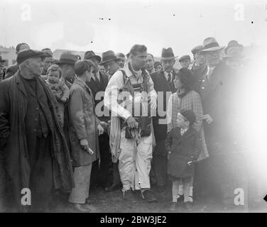 Birdman fliegt mit Flügeln auf Hanworth zur Erde. Clam Sohn, ein junger Amerikaner aus, Lansing Michigan, gab seine erste Ausstellung von "Vogel" Flug in großbritannien in Hanworth Air Park, Feltham, Middlesex. Einen Flügelanzug und eine Flosse an sich ziehen Sohn flog aus einer Höhe von etwa 10, 000 Fuß auf die Erde wie eine riesige Möwe. Er faltete seine Flügel und zog die Schnur eines Fallschirms, als er innerhalb von 1, 000 Fuß des Bodens, Foto zeigt Clem Sohn von einer Menge von Zuschauern umgeben, als er ging zu starten. Mai 1936 Stockfoto