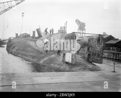 König Albert, einmal Stolz der deutschen Marine, wird in Rosyth gebrochen. Die Arbeit hat in Rosyth Dockyard, Schottland, auf die Auflösung der 20, 000 Tonnen Ex-deutschen Schlachtschiff König Albert, die von Scapa Fluss gerettet wurde, wo sie mit anderen deutschen Schiffen nach dem Krieg versenkt wurde begonnen. Der Hulk, der auf dem Kopf liegt, wird nach oben geschorben, damit das Wasser aus dem Dock herauslaufen kann. Foto zeigt, Arbeiter unter den massiven Propeller des König Albert beschäftigt, wie sie die Ausrüstung demontieren. 25 Mai 1936 Stockfoto